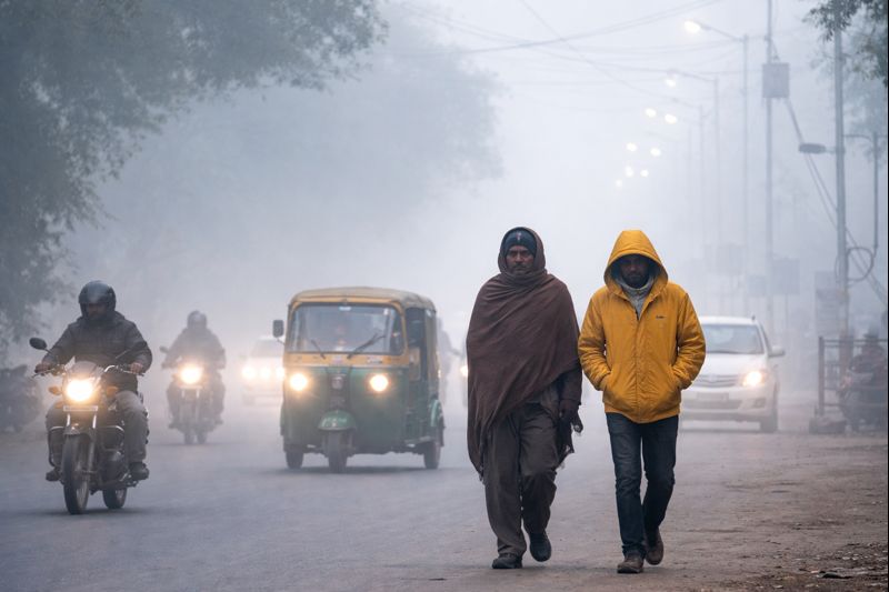 उत्तर प्रदेश में घने कोहरे और कड़ाके की ठंड के बीच सड़क पर चलते लोग और वाहनों की कम दृश्यता, सर्द मौसम से प्रभावित जनजीवन की वास्तविक तस्वीर